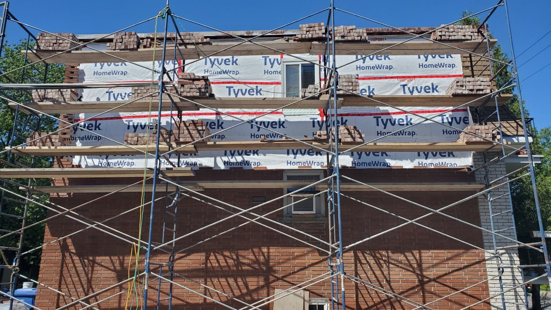 Un bâtiment en briques est en cours de rénovation avec des échafaudages autour.