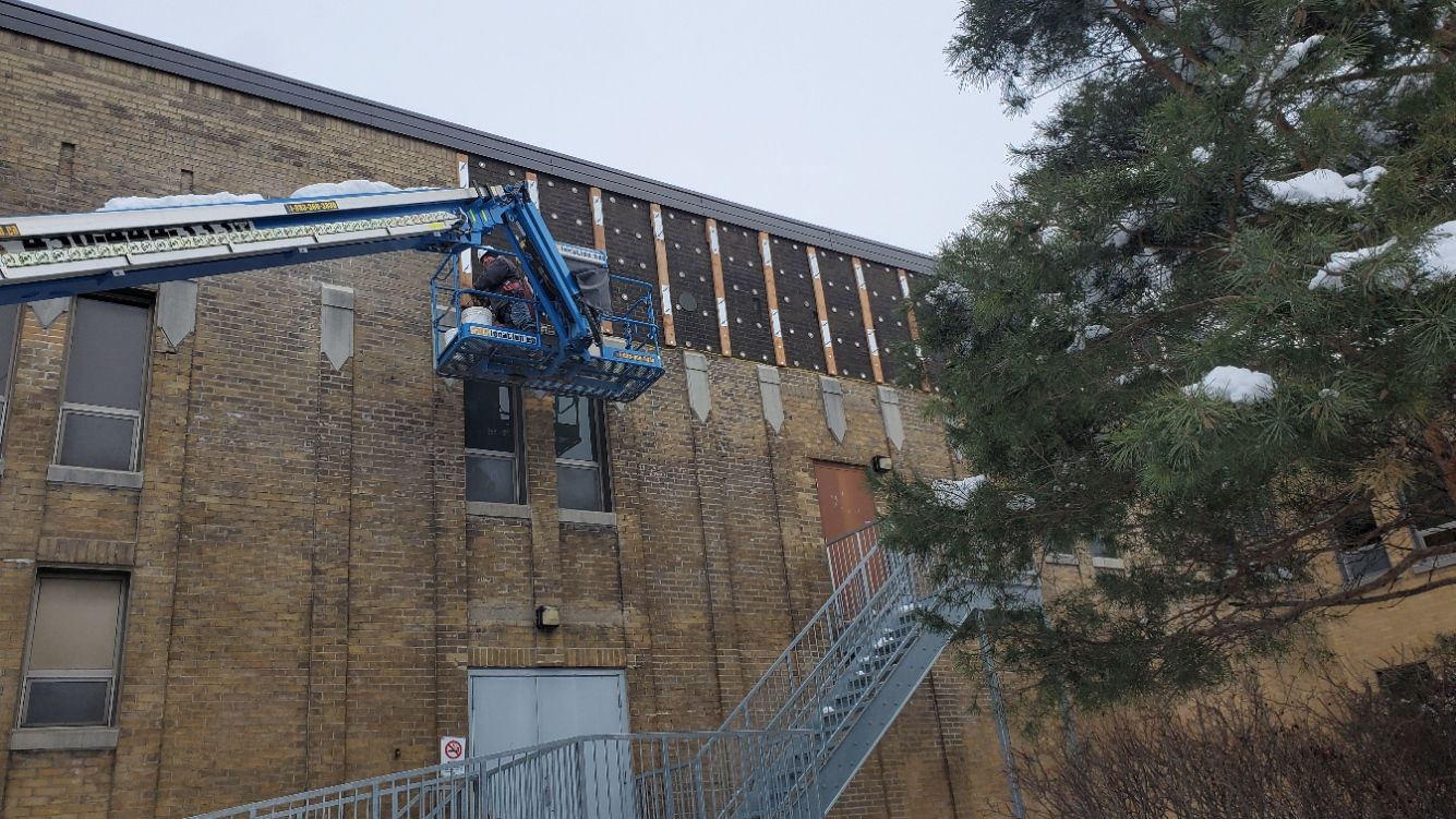 Un grand bâtiment en briques avec une grue au sommet.