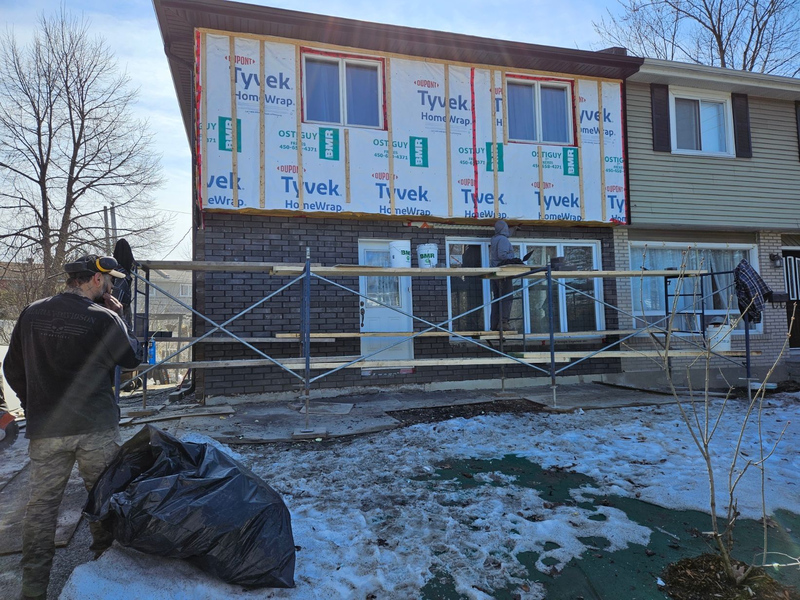 Un homme se tient devant une maison en construction.