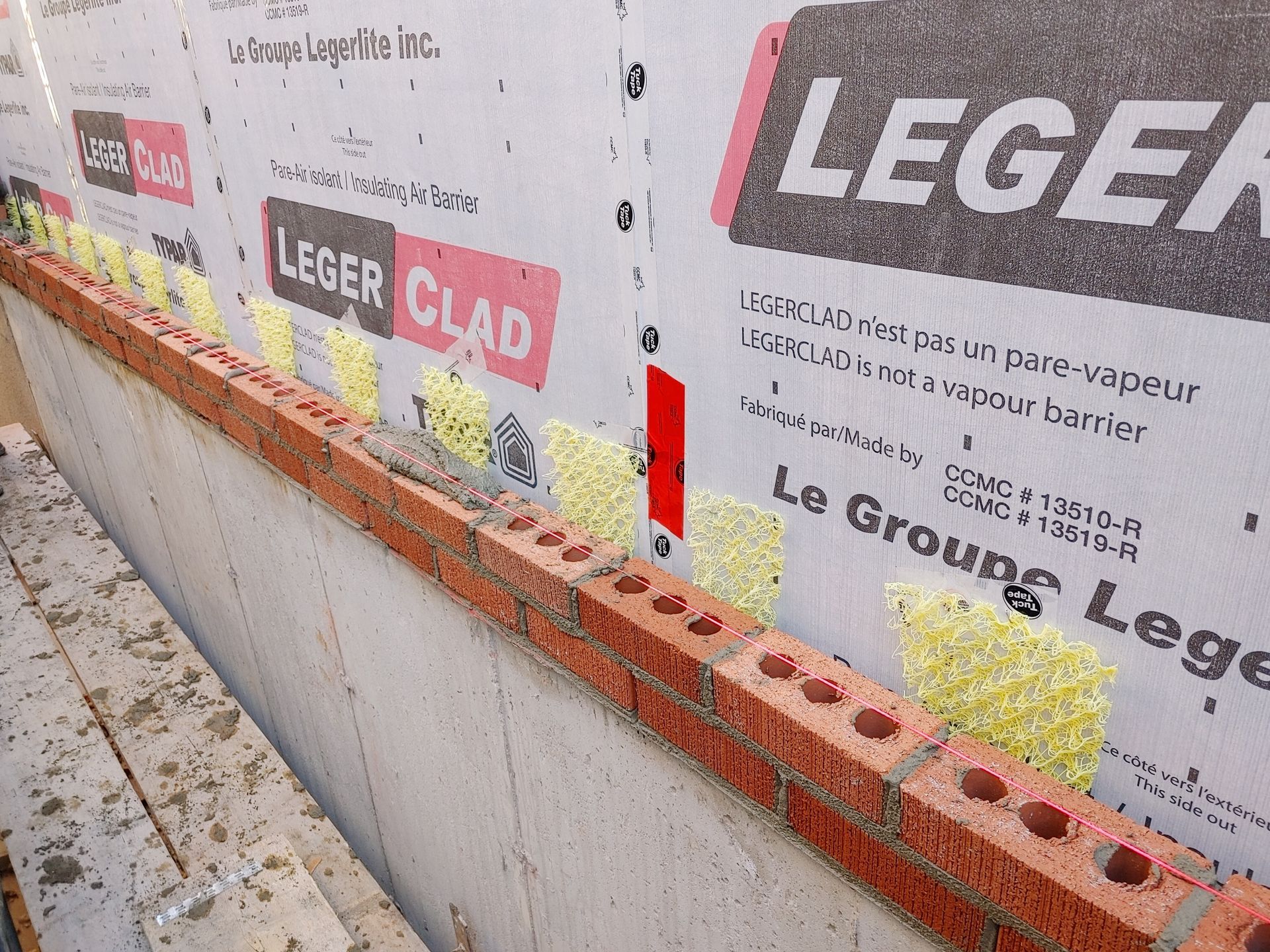 Un mur de briques est en cours de construction avec un produit de revêtement léger