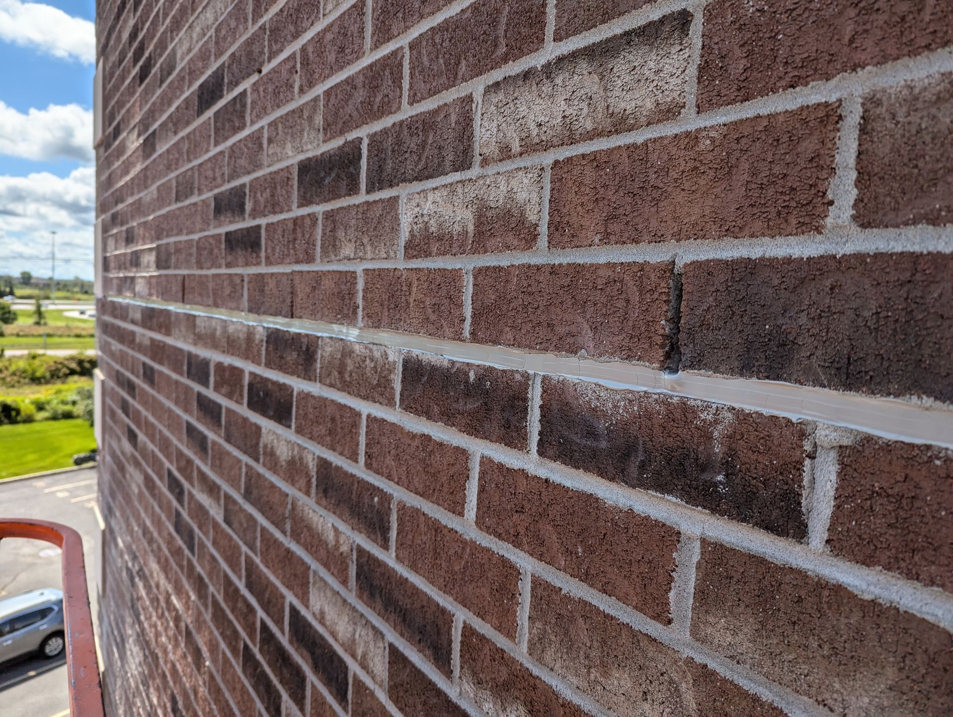 Un gros plan d'un mur de briques avec une voiture garée devant.