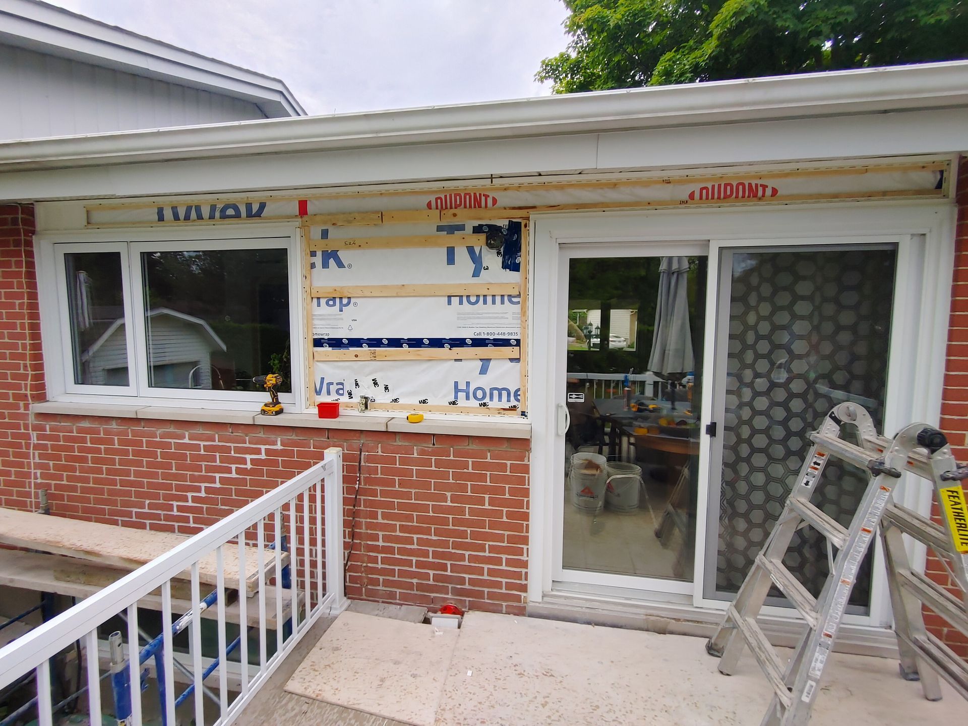 Une échelle est posée sur le côté d'une maison en briques.