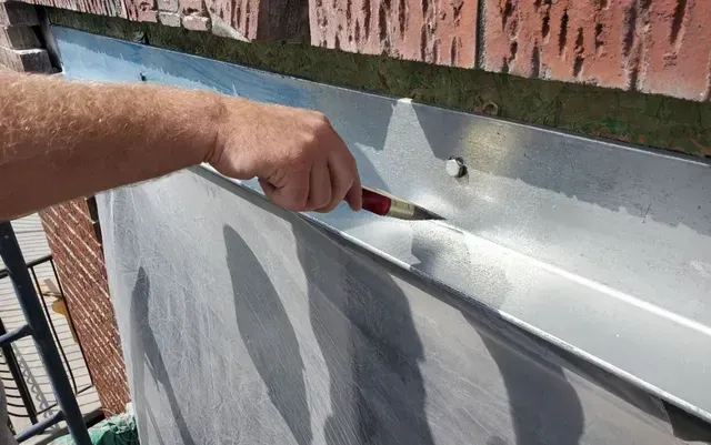 Un homme peint un mur de briques avec un pinceau.