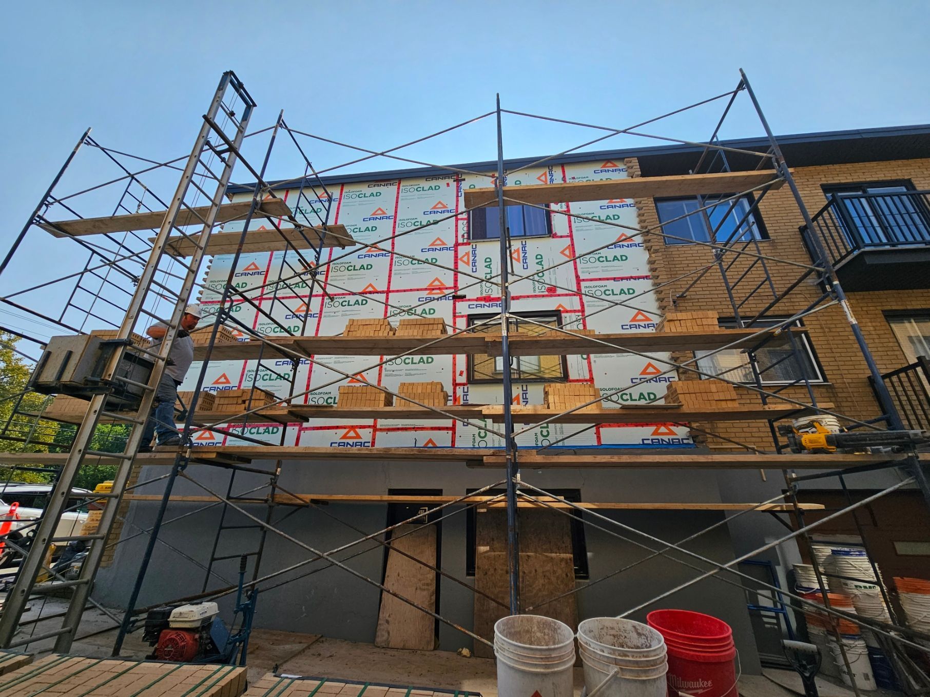 Un bâtiment est en cours de rénovation avec des échafaudages et des seaux.