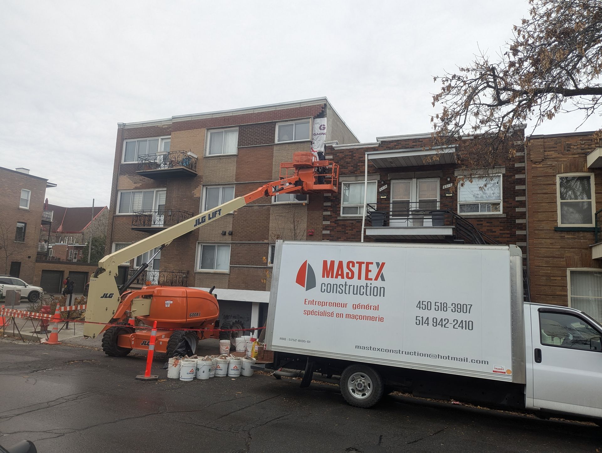 Un camion mastex blanc est garé devant un bâtiment