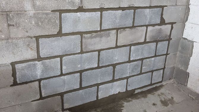 Un mur de briques est en train d'être construit dans un sous-sol.