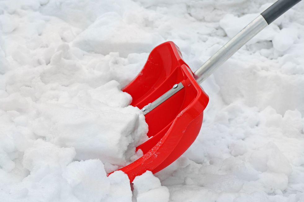 Red snow shovel scooping snow.