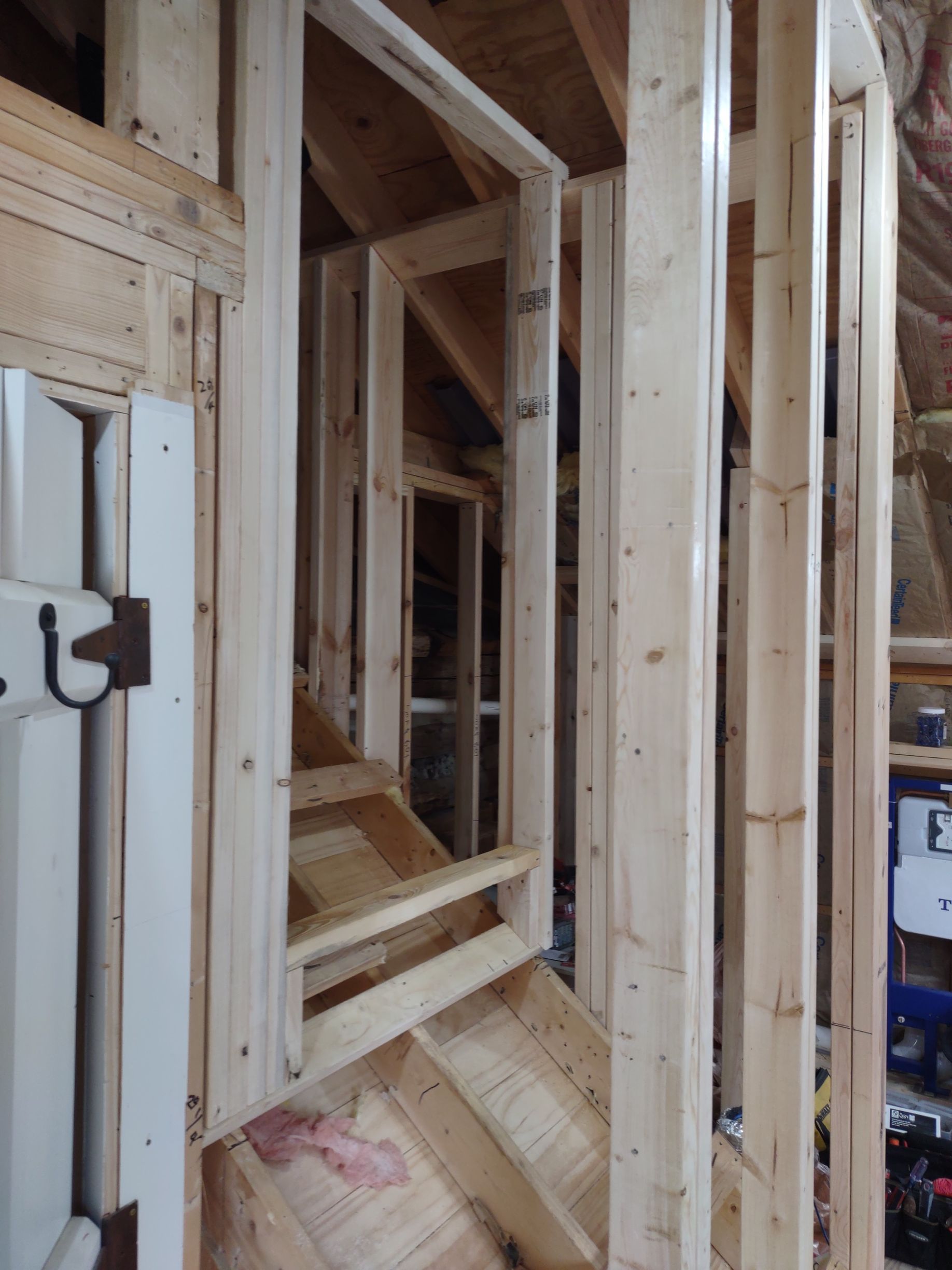 Framing of a small staircase and doorway within a home’s interior, with exposed wood.