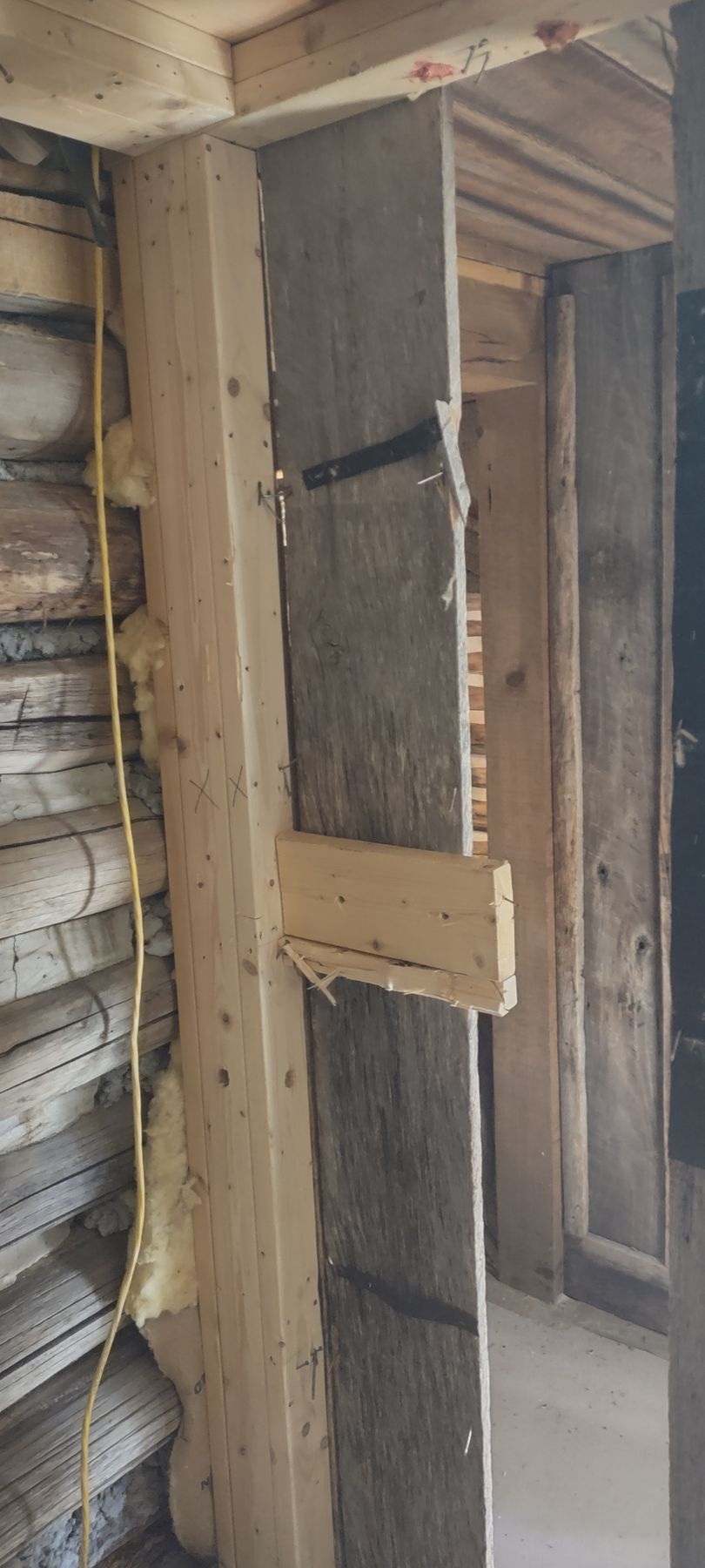 Wooden doorway frame under construction, with exposed boards, brick, and support beams.