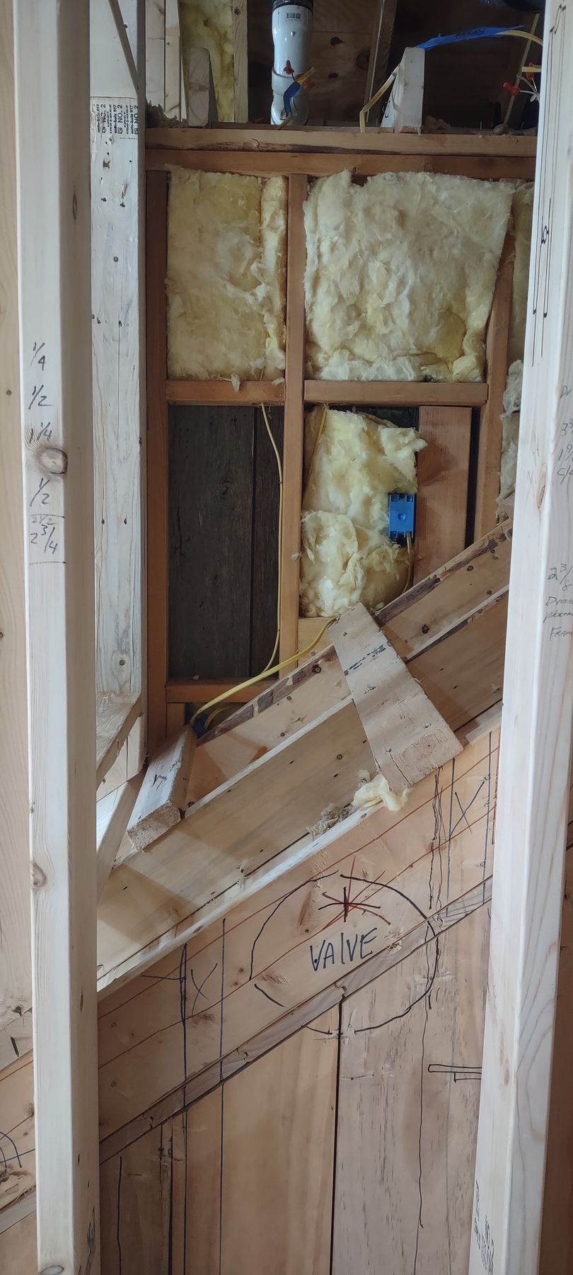 Interior framing with insulation, a blue electrical box, and angled wooden supports.