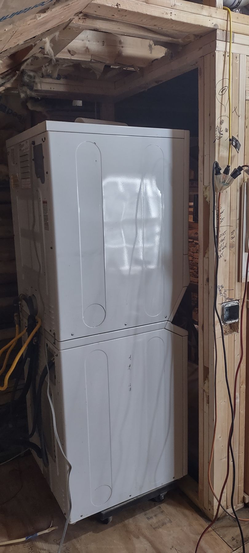 A stacked, white appliance, possibly a washer/dryer, sits inside a wooden-framed room.