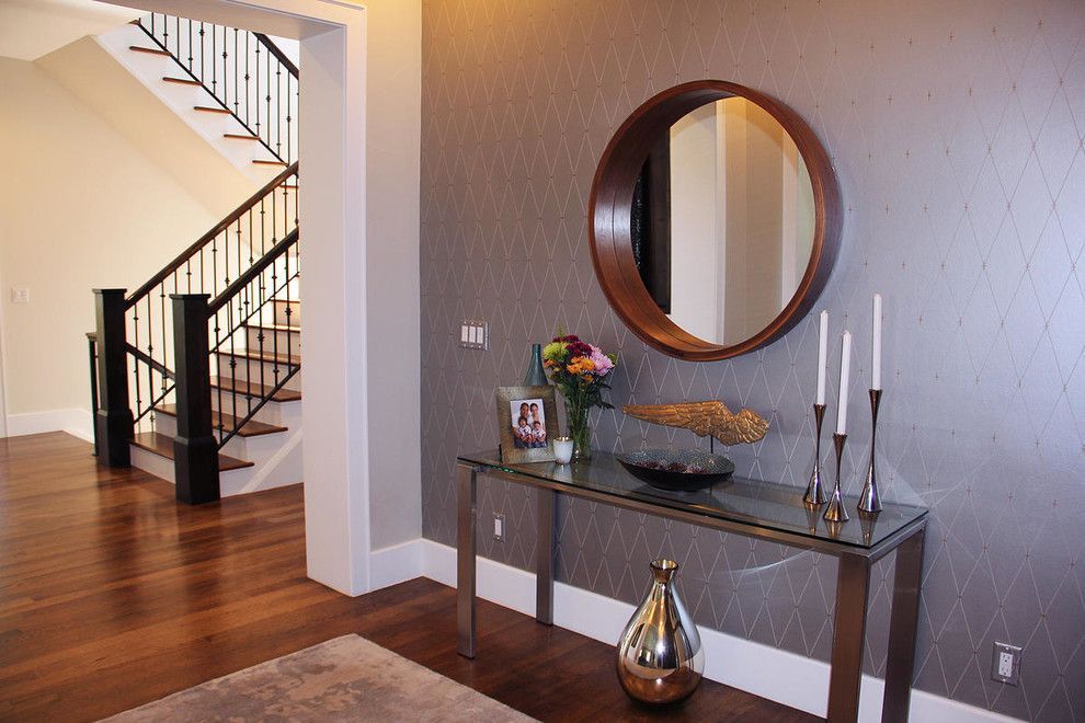 Denver home, Entryway with wooden floors, staircase, console table, mirror, and decorative items on a grey patterned wall.