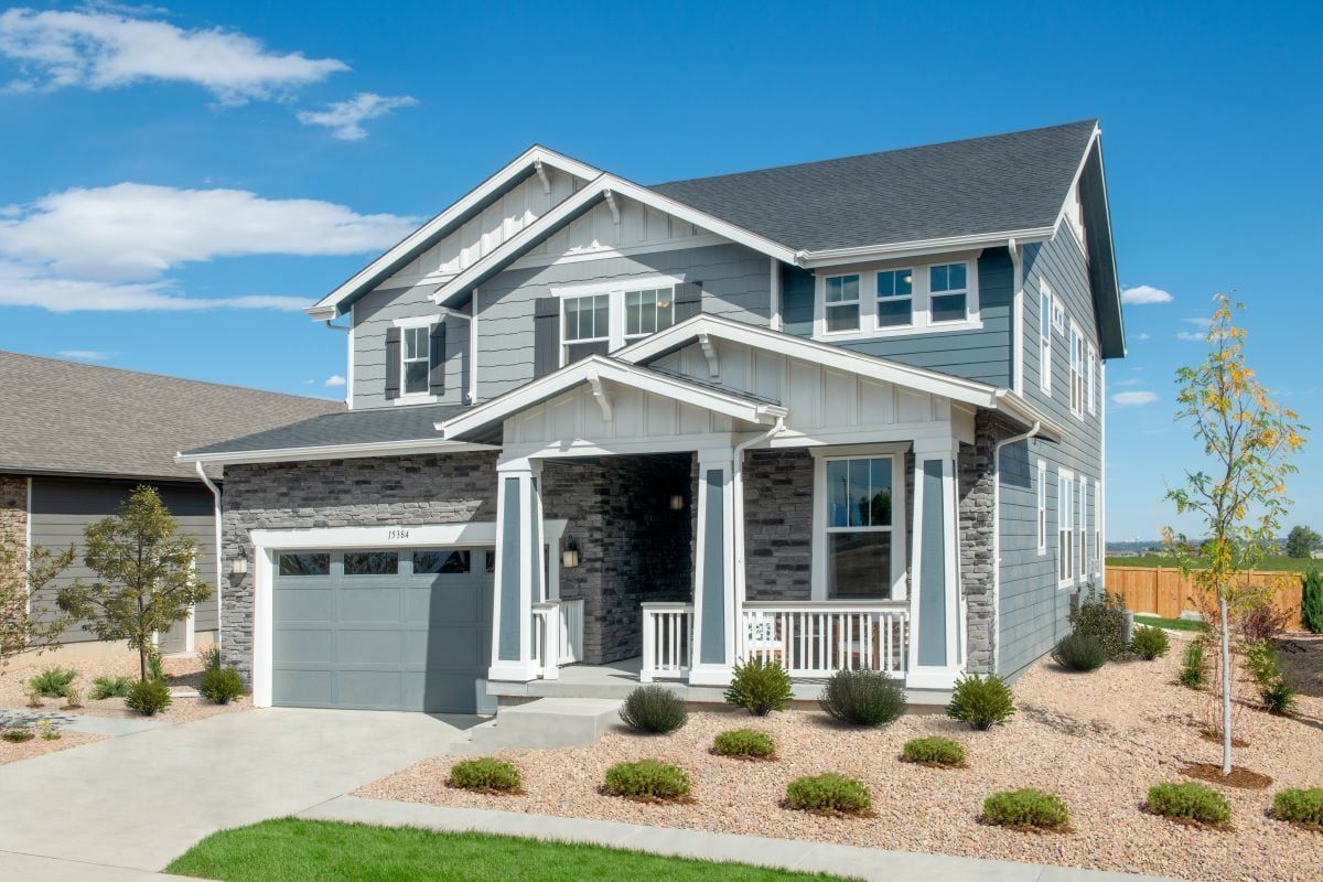 Denver remodel Two-story house with gray siding, a porch, and a blue sky in a residential area.