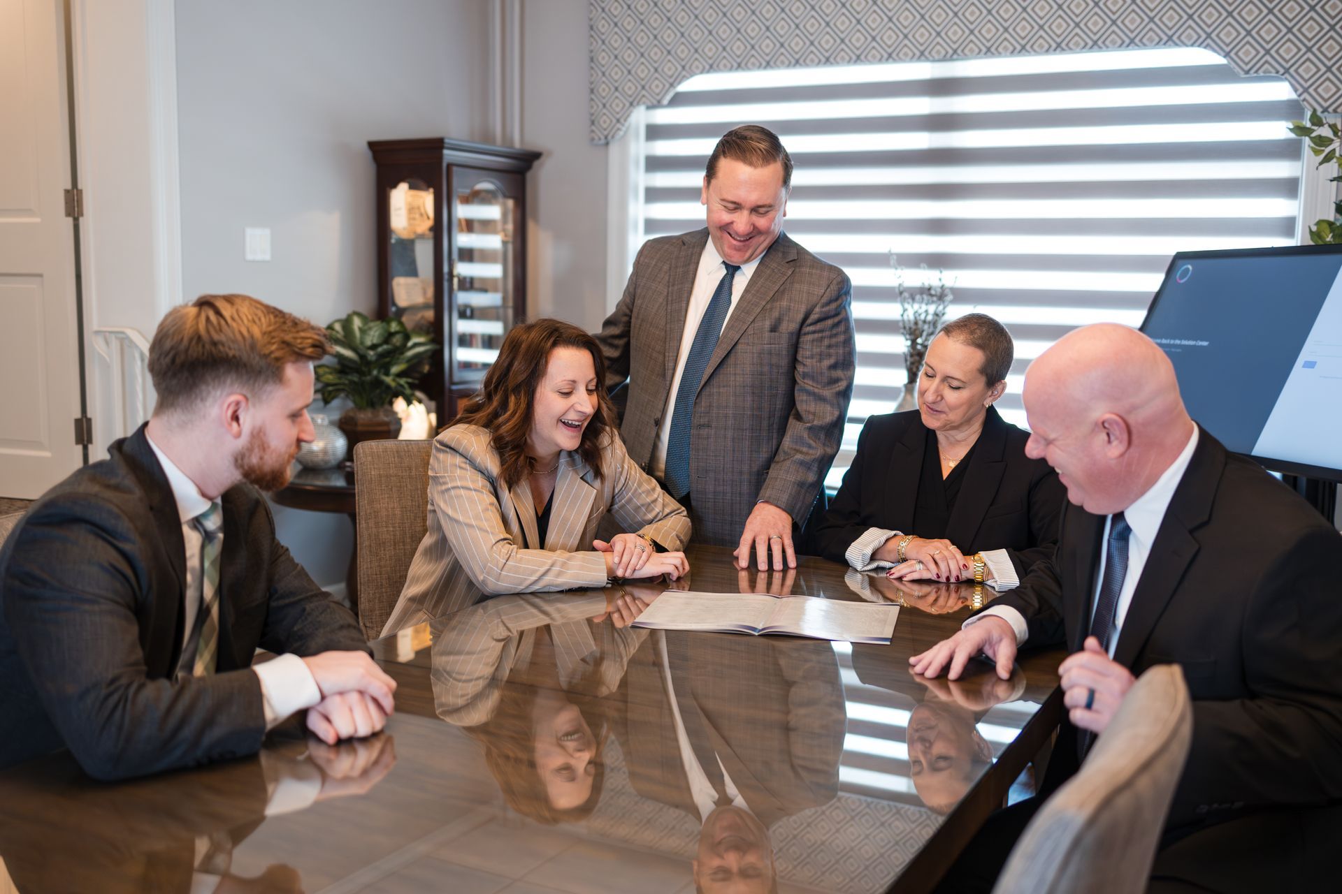 Man using laptop, woman writing in notebook at a table, both indoors.