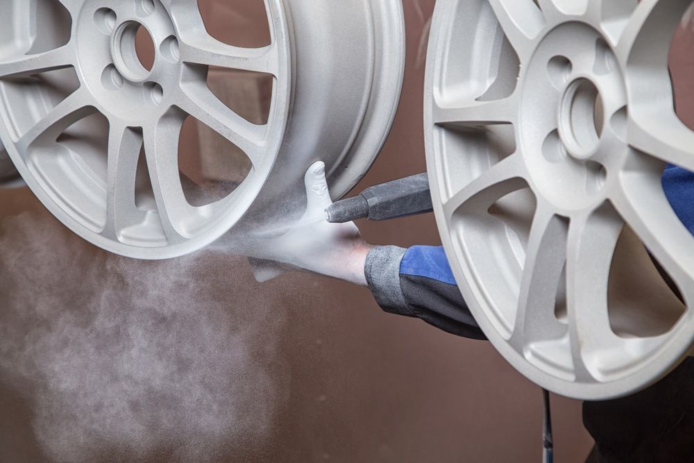 A Person Is Painting A Pair Of White Wheels — Mudgee Powder Coat Pty Ltd in Mudgee, NSW