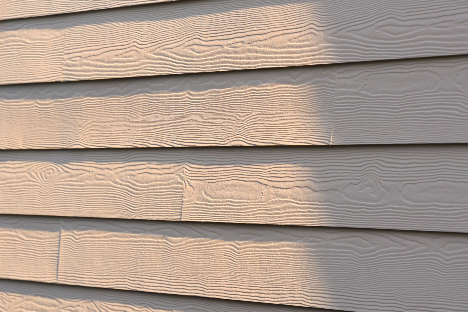 A close up of a house siding with a shadow on it.