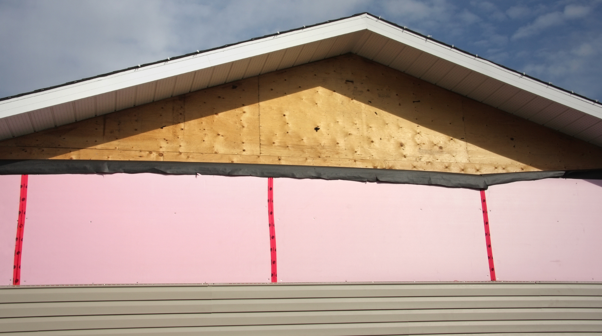 The roof of a house is being built with pink insulation.