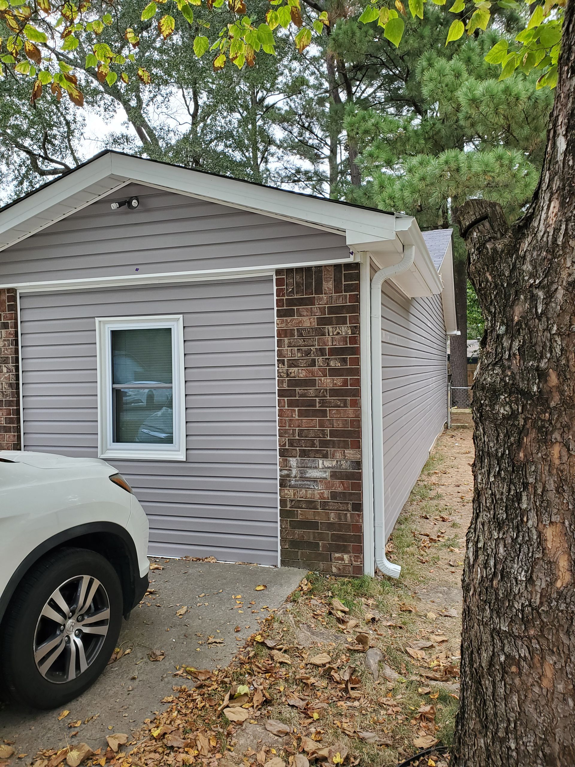 Mastic Carvedwood44 Dutchlap vinyl siding in Harbor Grey. 5” seamless gutters and downspouts in white.