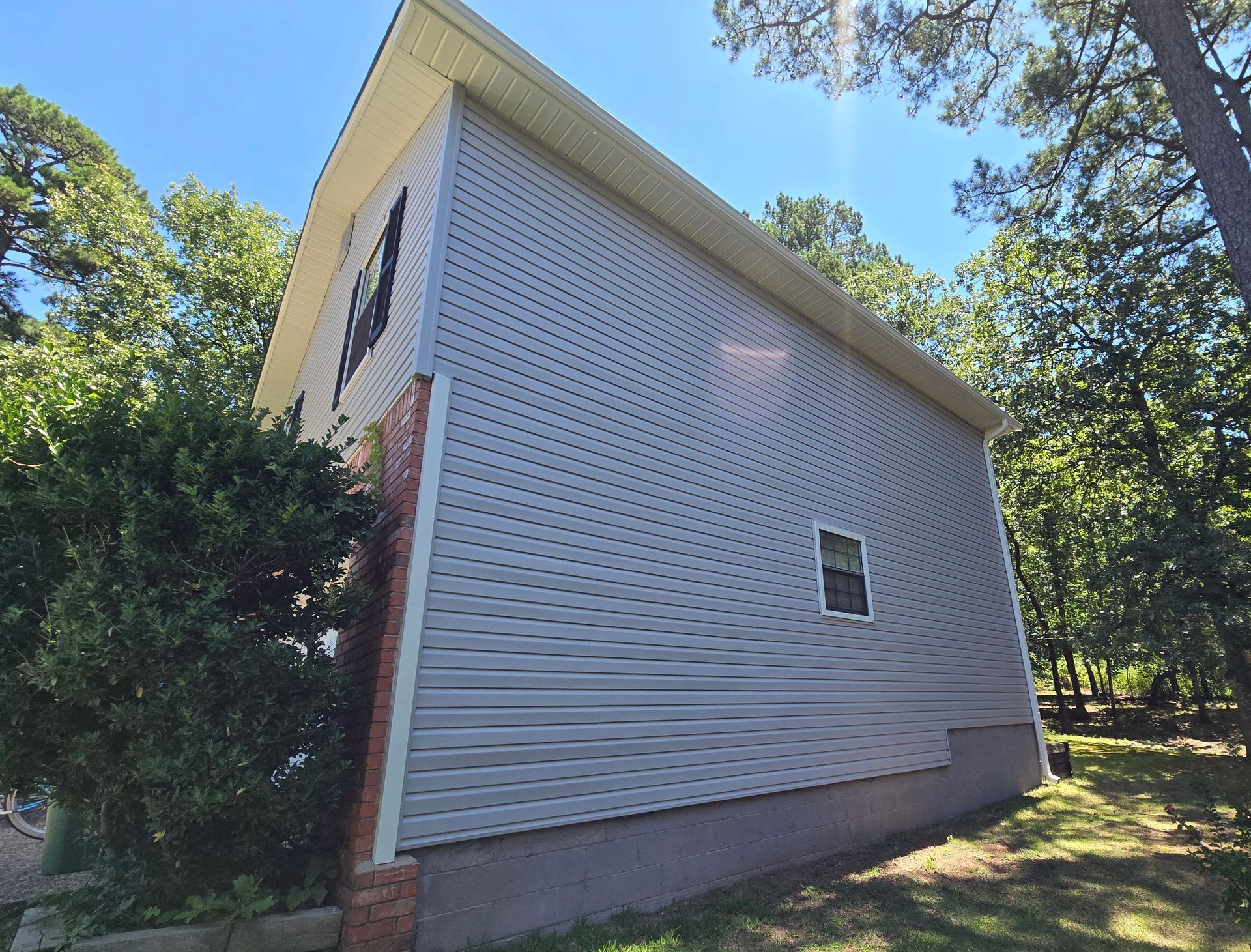 Mastic Carvedwood44 Dutchlap vinyl siding in Victorian Grey. 5” seamless gutters, downspouts, and all trim in Linen. window shutters in black