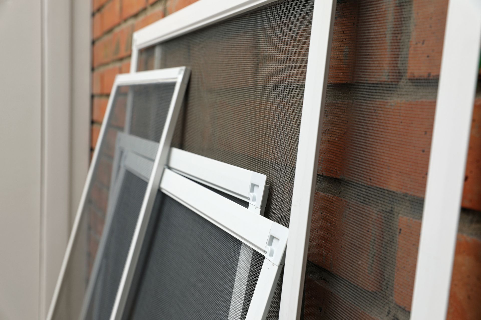 A stack of mosquito screens sitting on top of each other on a brick wall.
