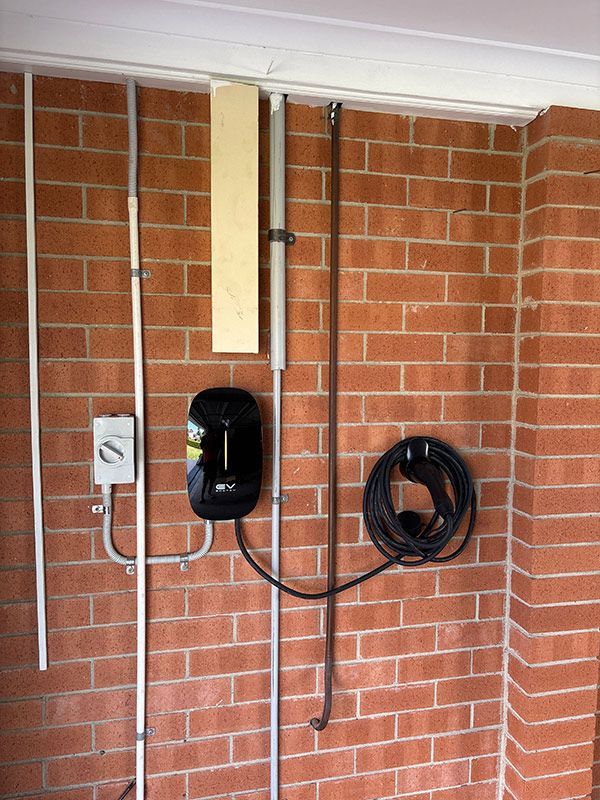 A Brick Wall With a Charger Attached to It — Rapid Sparky in Dapto, NSW