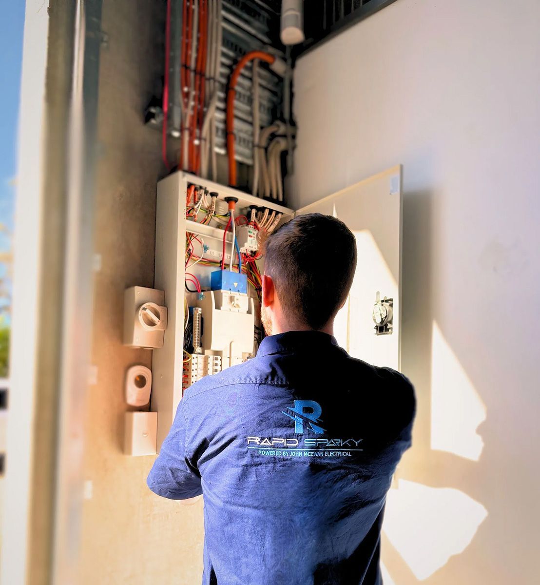 Electrician Working on Electrical Panel Mounted on a Wall — Rapid Sparky in Wollongong, NSW