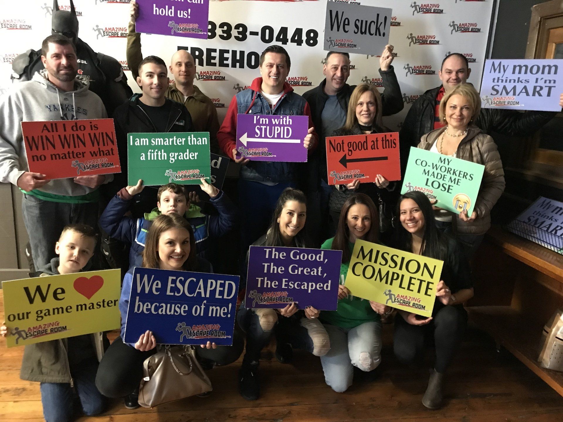 Group of people hold signs after an escape room game. Signs say 