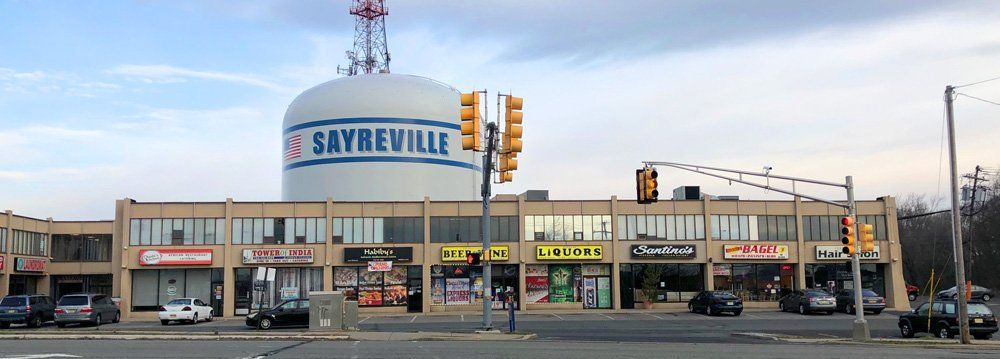 A Sayreville shopping center with a water tower in the background, blue sky.