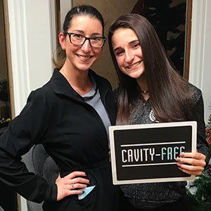 Two women smiling, holding a sign that reads