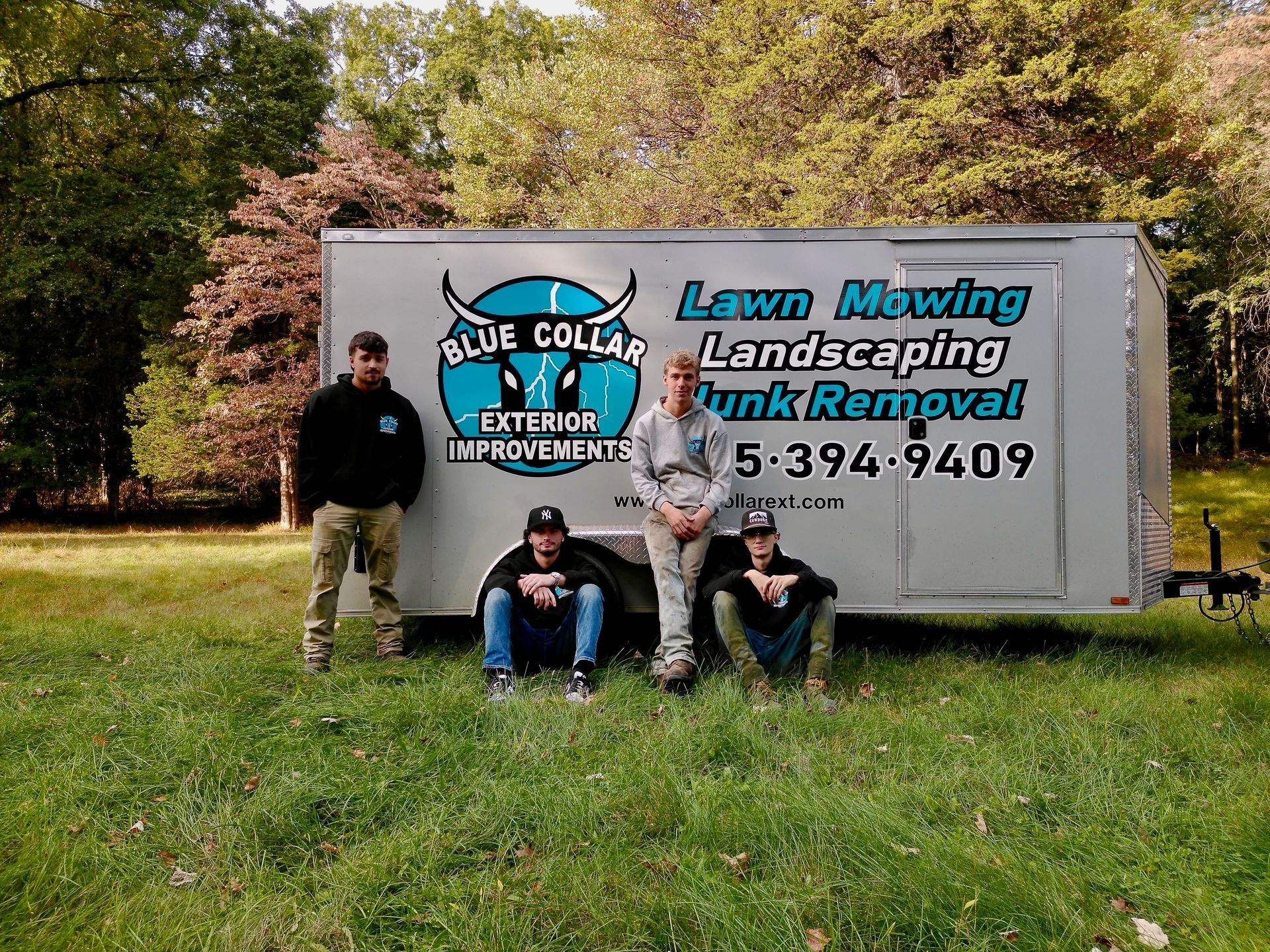 Four people pose in front of a trailer with
