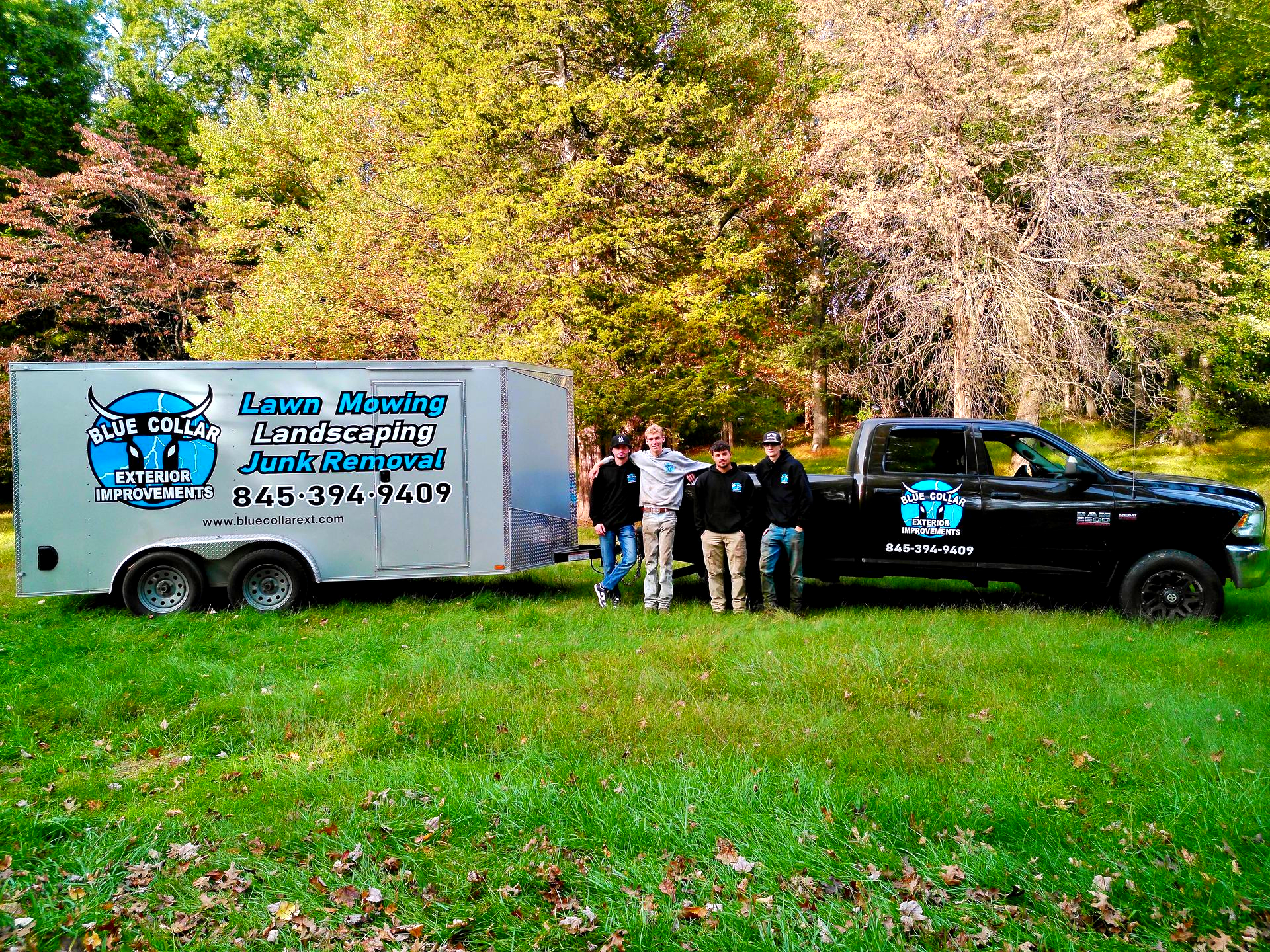 Crew posing by a black truck and trailer.