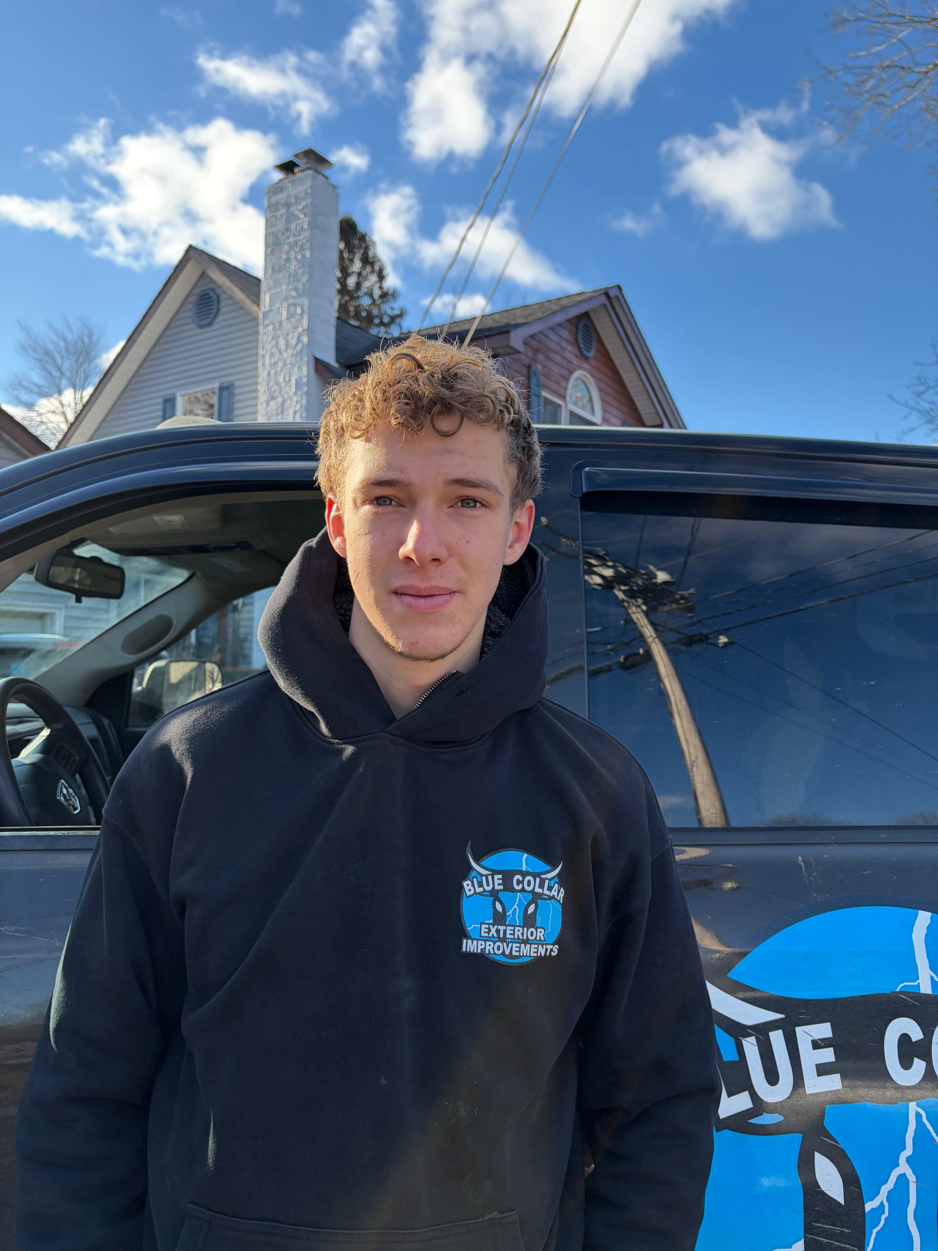 Man in black hoodie stands next to a truck with 