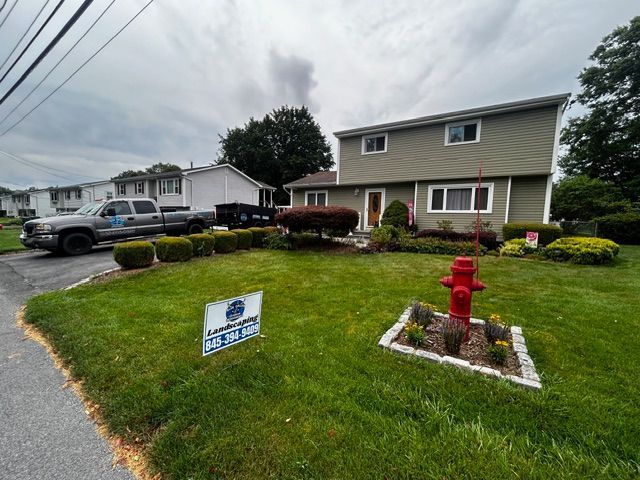A two-story building with green siding and a red fire hydrant in front on a sunny day.