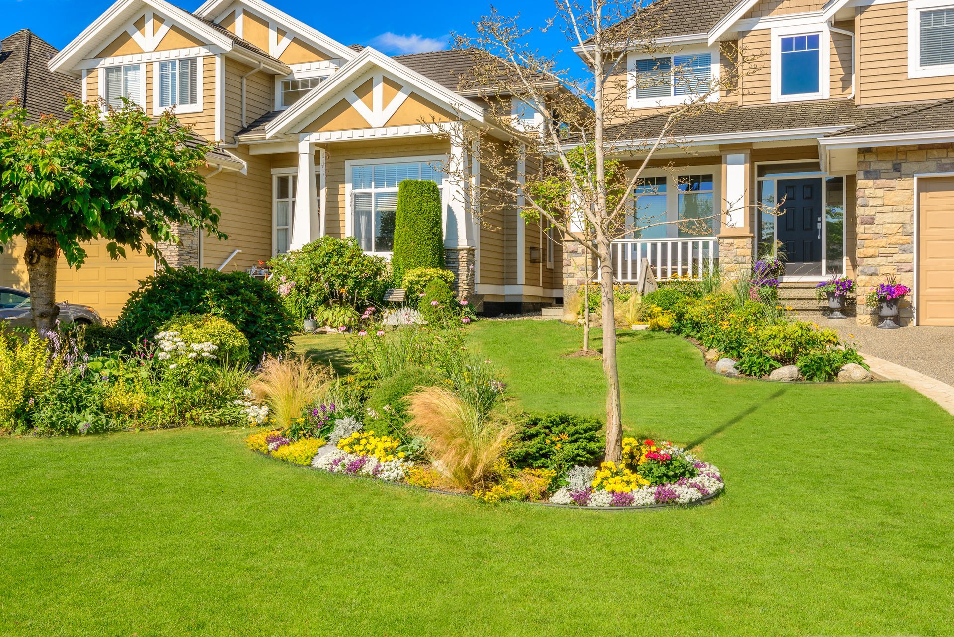 Suburban house with a lush green lawn and colorful flower bed in front yard
