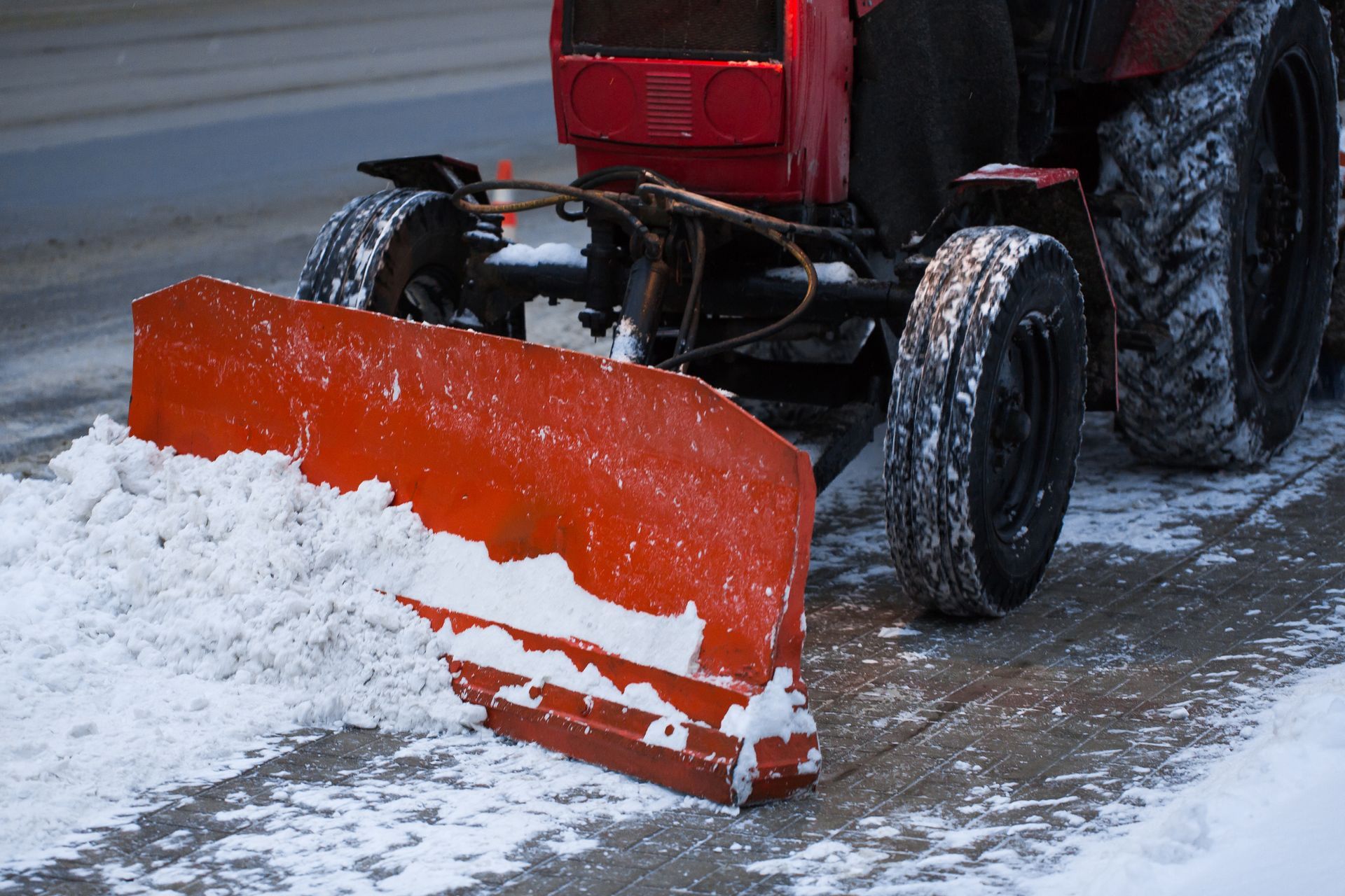 Red snowplow clearing snow from a road.