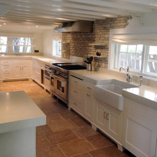 A kitchen with white cabinets, concrete countertops, a sink and a stove