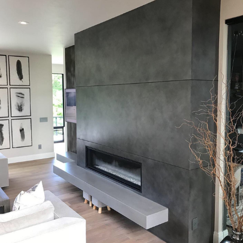 A living room with a concrete fireplace and a television on the wall.