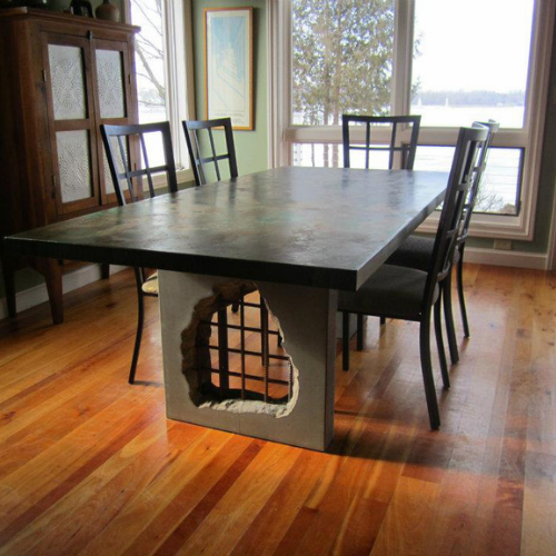 A concrete dining room table with a hole carved in the middle of the base.