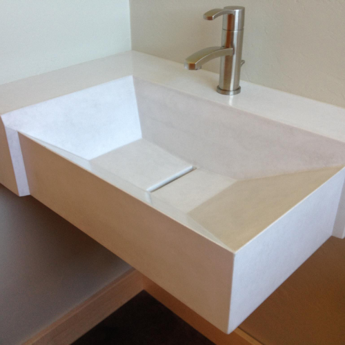 A concrete bathroom sink with a faucet on top of it