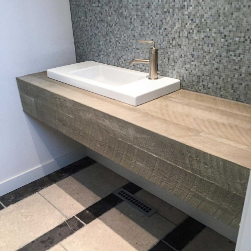A concrete bathroom sink is sitting on top of a wooden counter.