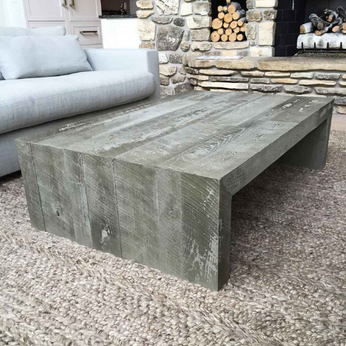 A concrete coffee table is sitting next to a couch in a living room.