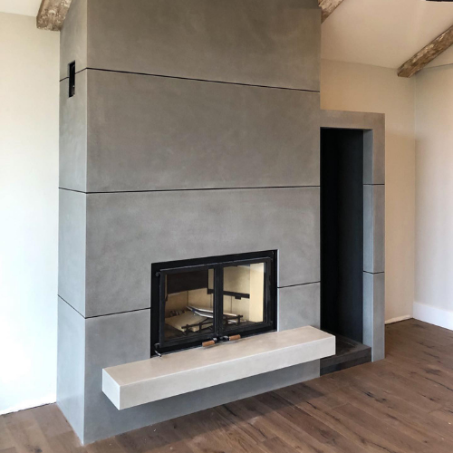 There is a concrete fireplace in the middle of the room.