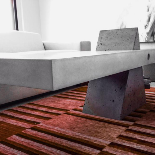 A concrete bench is sitting on a red rug in a living room.