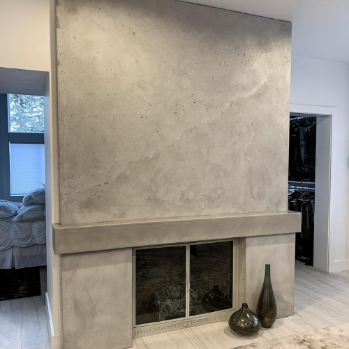 There is a concrete fireplace in the middle of the room.