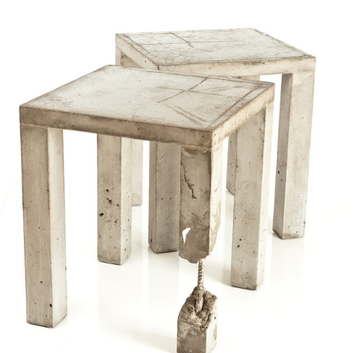 Two concrete tables with a statue of a hand on one of them