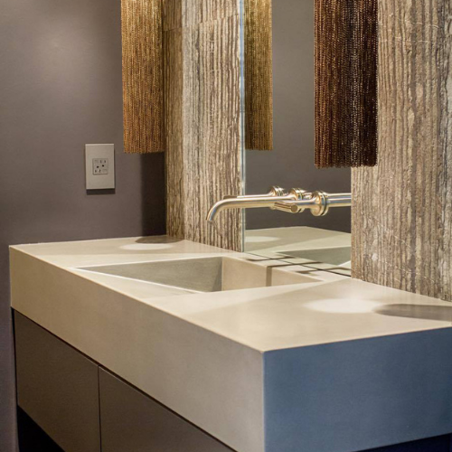 A bathroom with two concrete sinks and a mirror