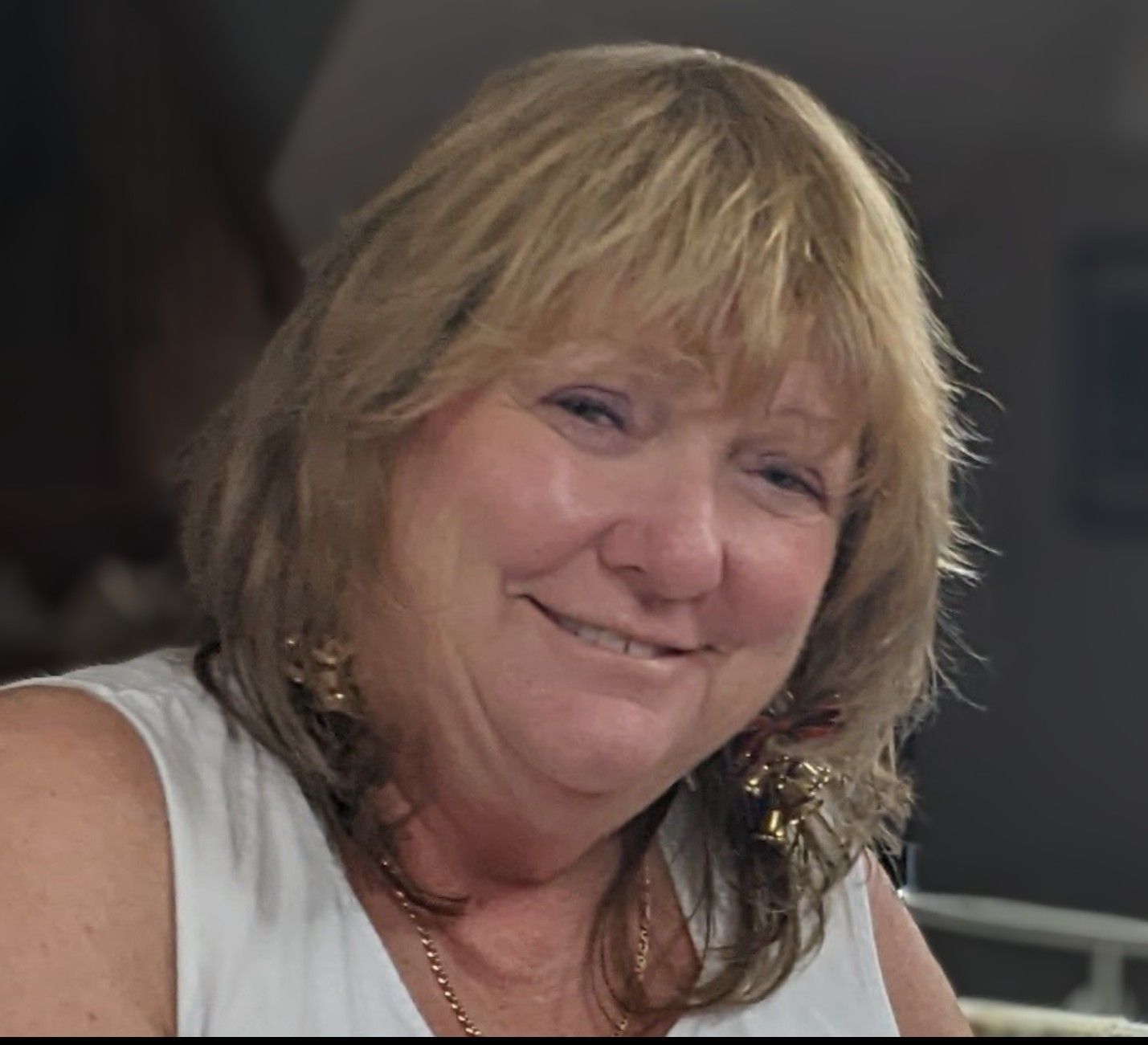 A woman in a white tank top smiles for the camera