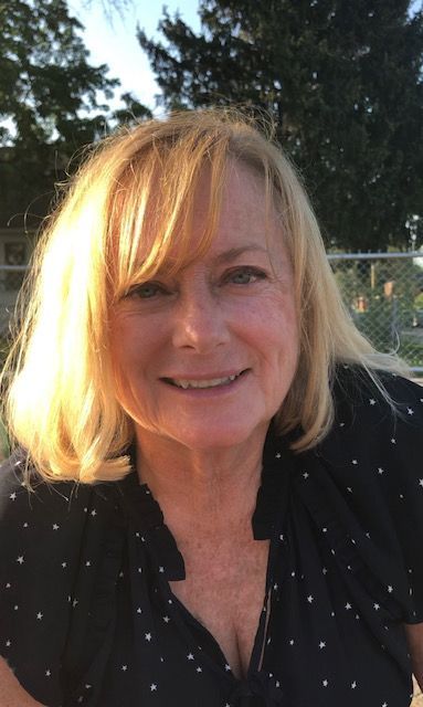 A woman with blonde hair and a black shirt is smiling for the camera.