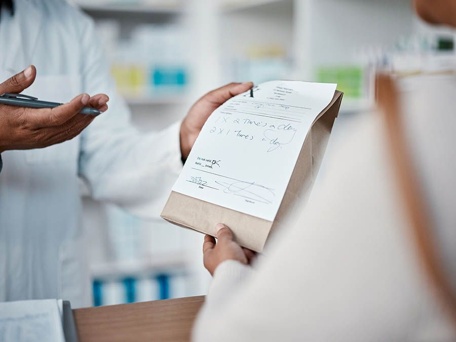 A pharmacist is giving a prescription to a patient in a pharmacy.