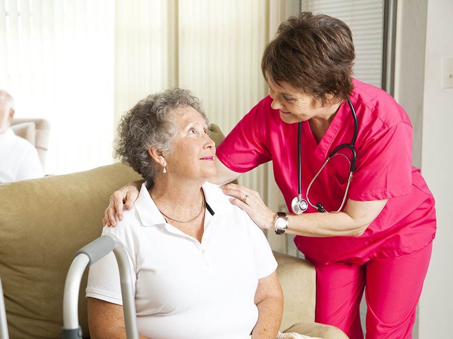 A nurse is talking to an elderly woman in a wheelchair.